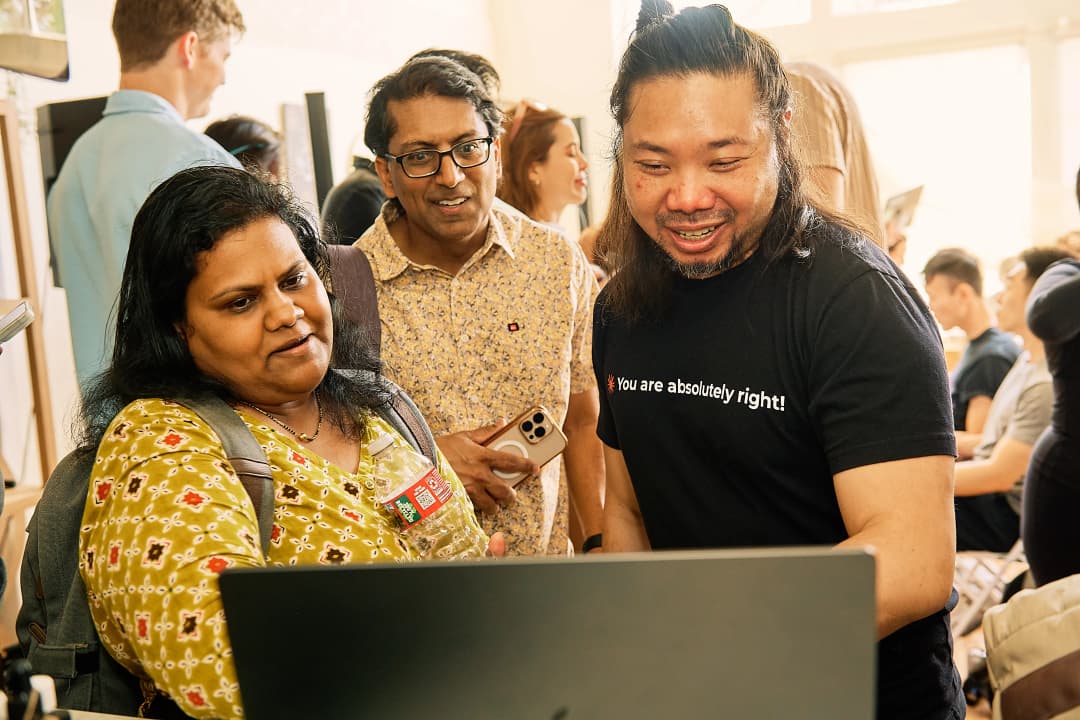 Three attendees looking at a laptop screen together