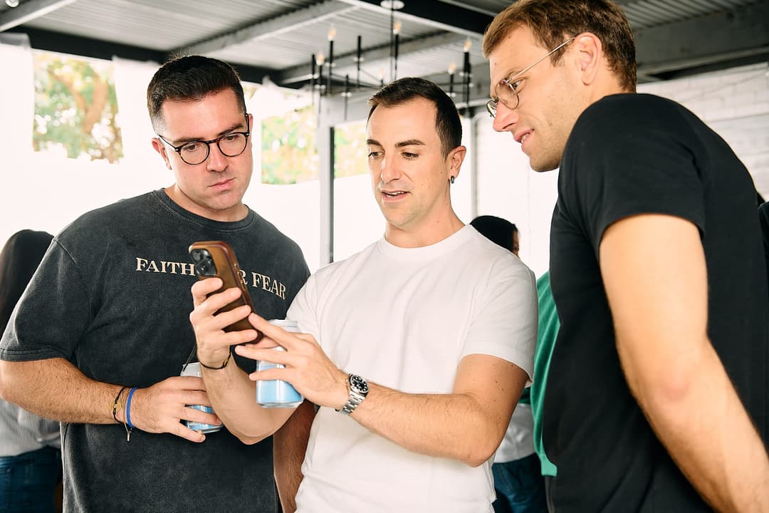 Three attendees looking at a phone during the meetup