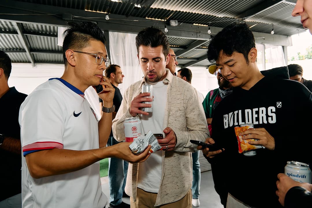 Three attendees looking at a phone by the patio doors