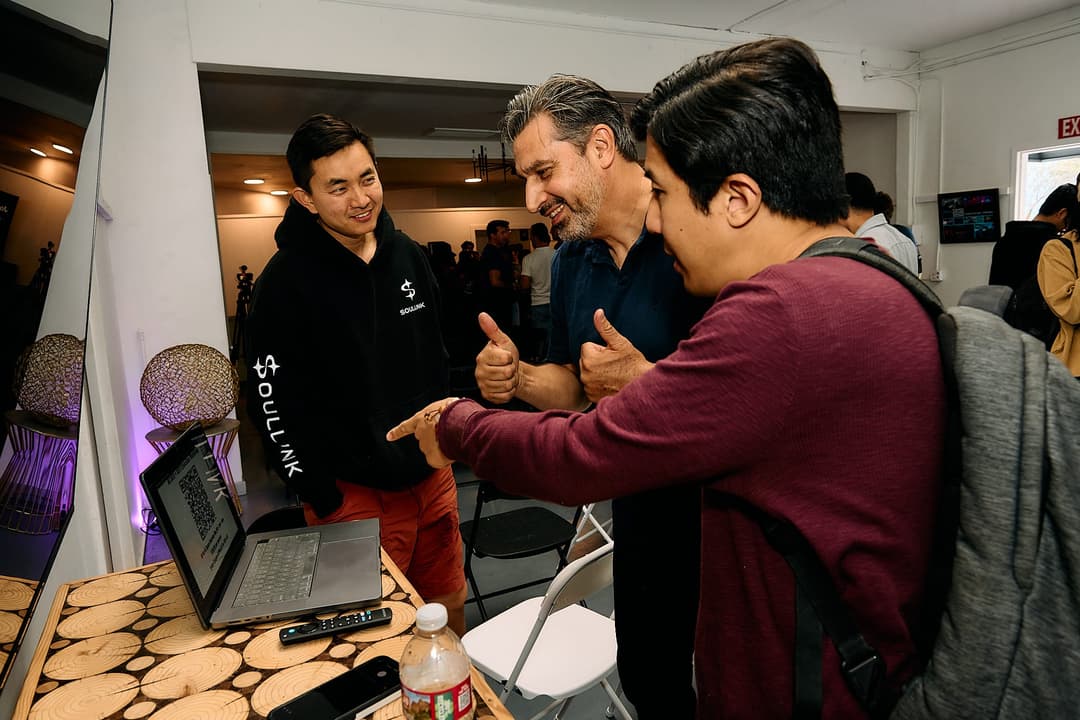 A group huddled around a laptop demo after the event