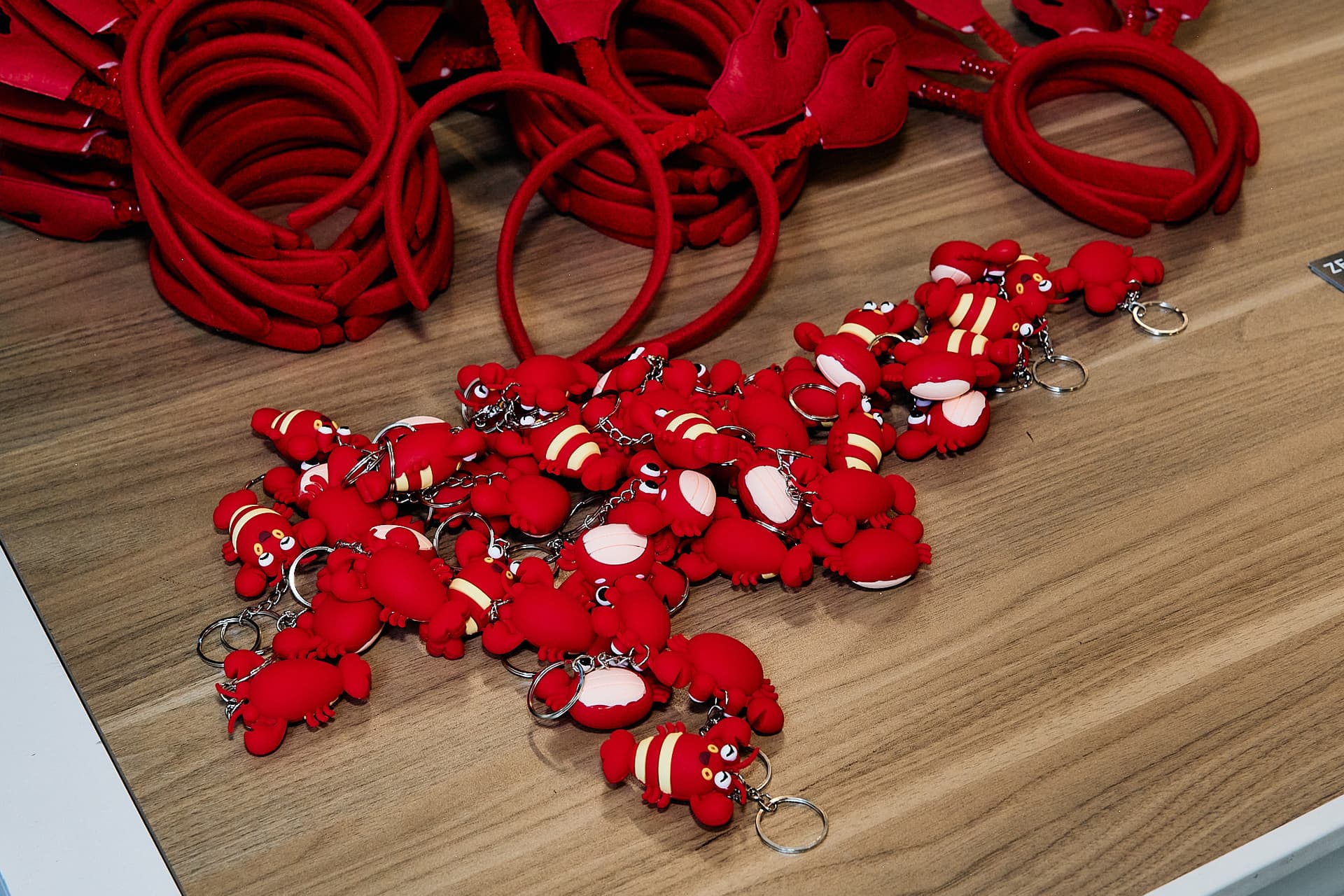 A pile of red lobster headbands and keychains on a table